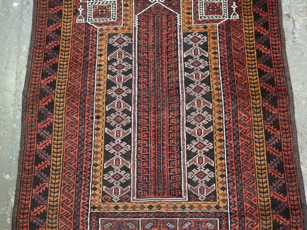 An antique hand-knotted Afghan Baluch wool prayer rug featuring a triple mihrab architectural design in burgundy, brown, ochre, and white tones. View IV