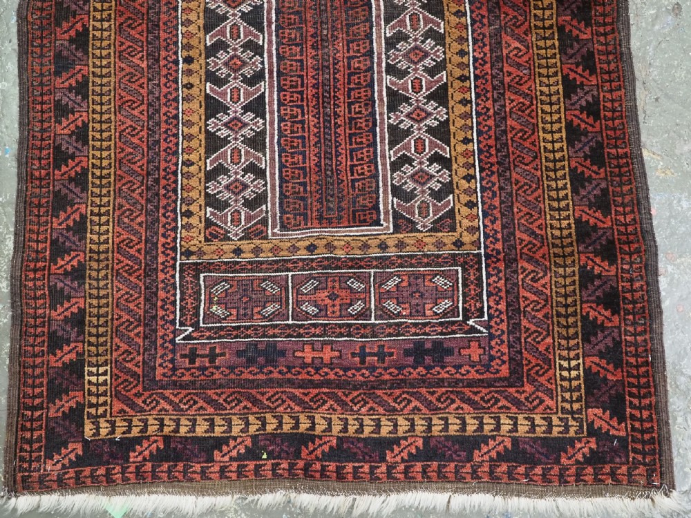 An antique hand-knotted Afghan Baluch wool prayer rug featuring a triple mihrab architectural design in burgundy, brown, ochre, and white tones. View V