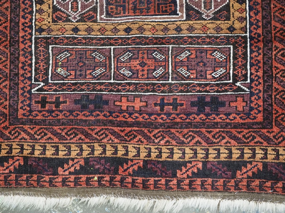 An antique hand-knotted Afghan Baluch wool prayer rug featuring a triple mihrab architectural design in burgundy, brown, ochre, and white tones. View X