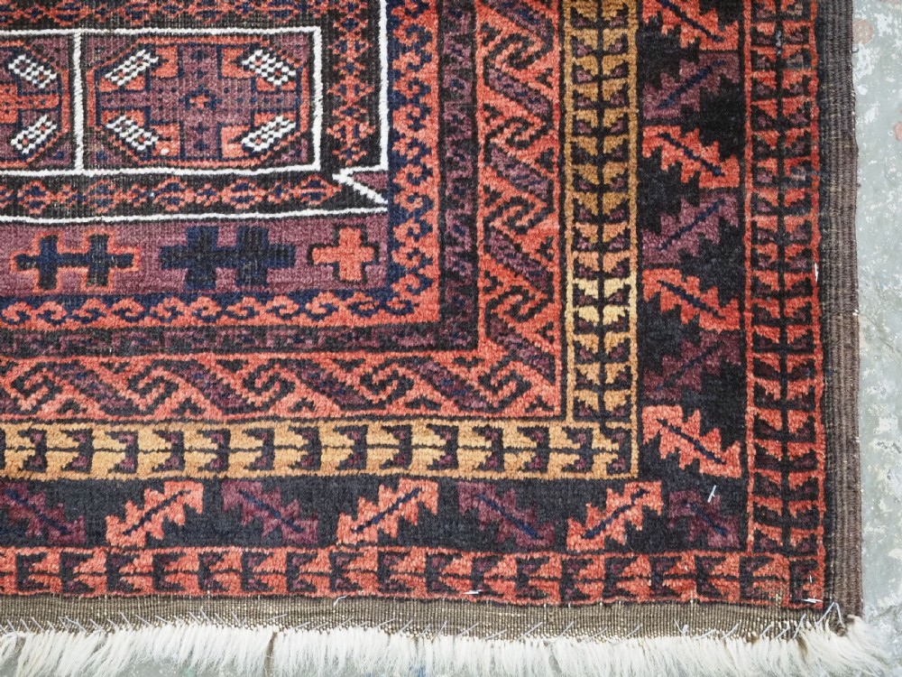 An antique hand-knotted Afghan Baluch wool prayer rug featuring a triple mihrab architectural design in burgundy, brown, ochre, and white tones. View XI