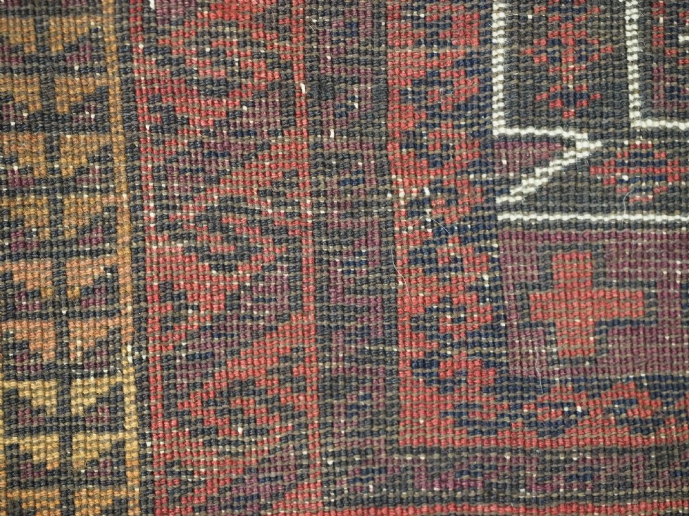 An antique hand-knotted Afghan Baluch wool prayer rug featuring a triple mihrab architectural design in burgundy, brown, ochre, and white tones. View XII