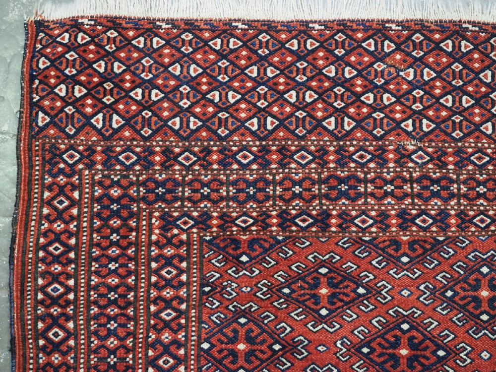 A hand-knotted wool Yomut Turkmen rug featuring a deep red field decorated with a dense repeating lattice pattern in navy, ivory, and brown tones. View V