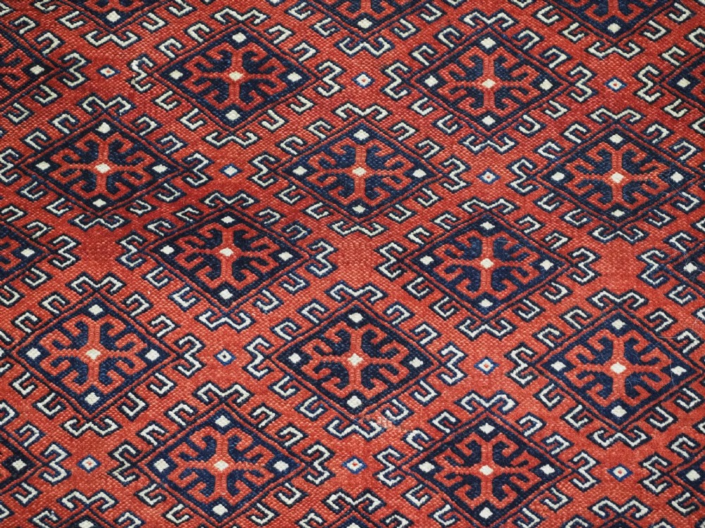 A hand-knotted wool Yomut Turkmen rug featuring a deep red field decorated with a dense repeating lattice pattern in navy, ivory, and brown tones. View VIII