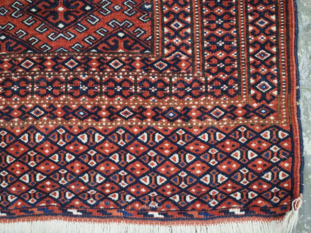 A hand-knotted wool Yomut Turkmen rug featuring a deep red field decorated with a dense repeating lattice pattern in navy, ivory, and brown tones. View XI