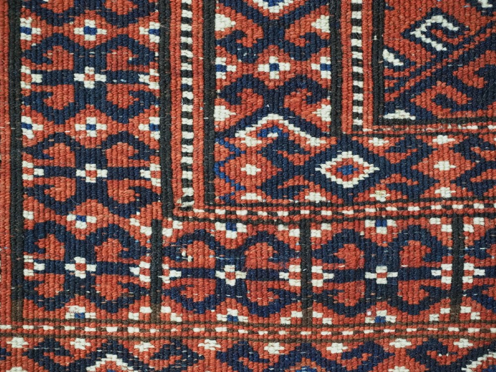 A hand-knotted wool Yomut Turkmen rug featuring a deep red field decorated with a dense repeating lattice pattern in navy, ivory, and brown tones. View XII