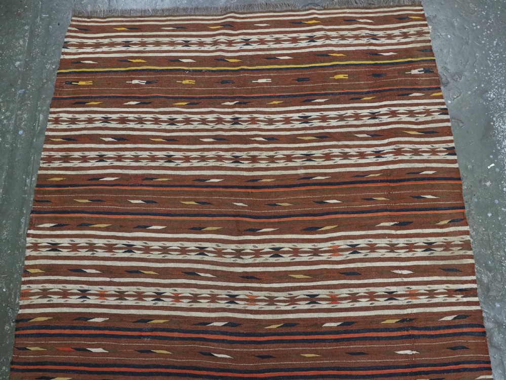 An antique flatweave Turkmen Dali wool kilim rug featuring horizontal bands of terracotta brown, cream, ochre, and dark navy geometric patterns. View III