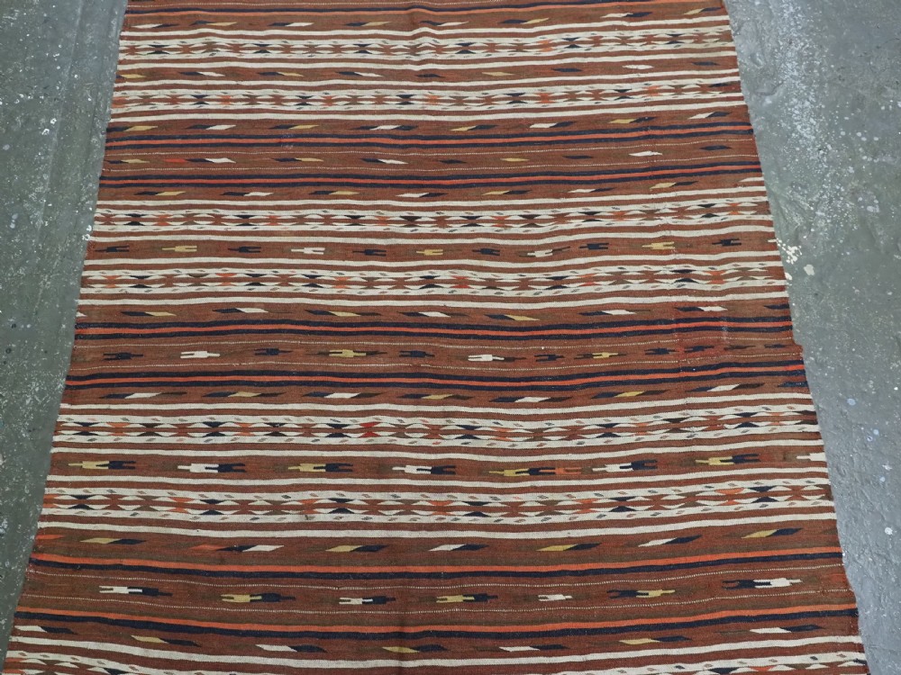 An antique flatweave Turkmen Dali wool kilim rug featuring horizontal bands of terracotta brown, cream, ochre, and dark navy geometric patterns. View IV