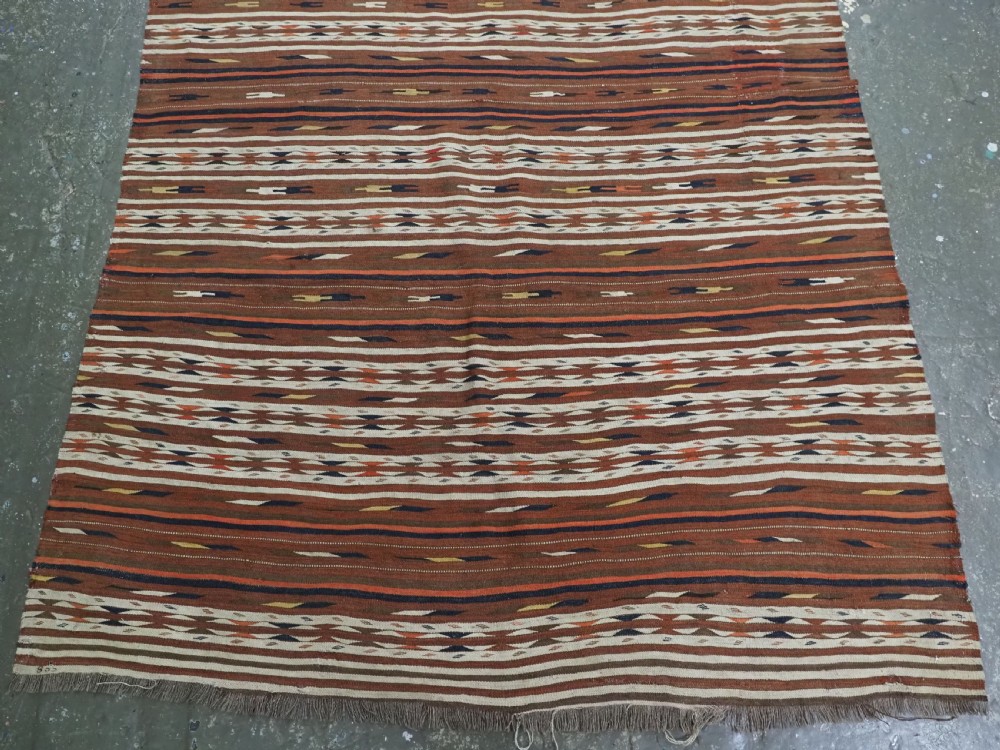 An antique flatweave Turkmen Dali wool kilim rug featuring horizontal bands of terracotta brown, cream, ochre, and dark navy geometric patterns. View V