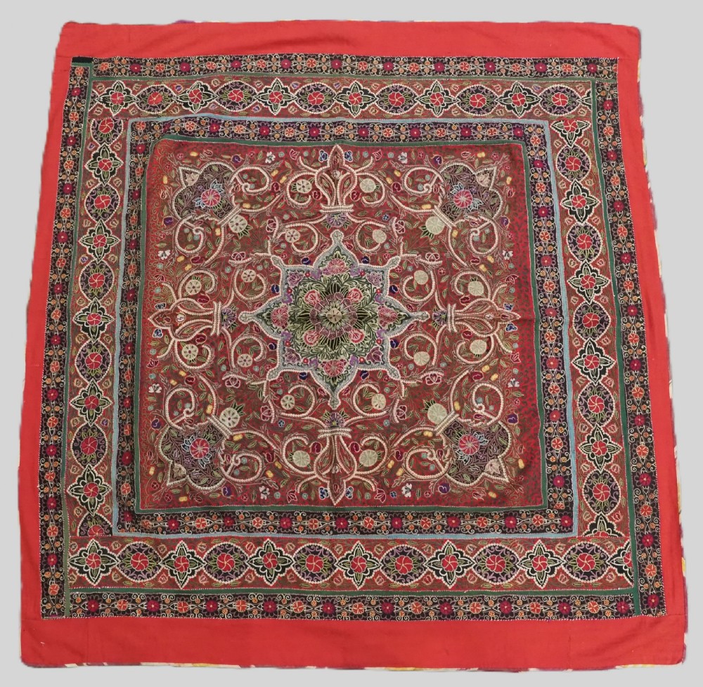 Square antique Persian Rasht embroidery featuring a central green and pink star medallion surrounded by floral motifs on red wool felt with decorative patterned borders.