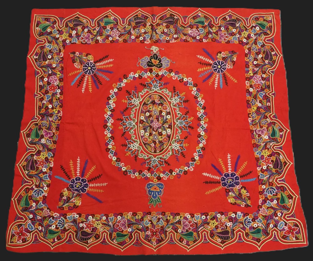 A square red felt textile decorated with polychrome silk chain-stitch embroidery and floral medallion applique motifs. View II