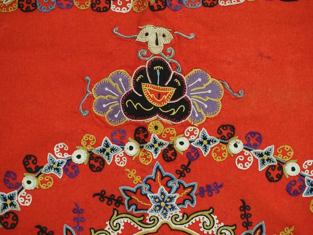 A square red felt textile decorated with polychrome silk chain-stitch embroidery and floral medallion applique motifs. View VIII