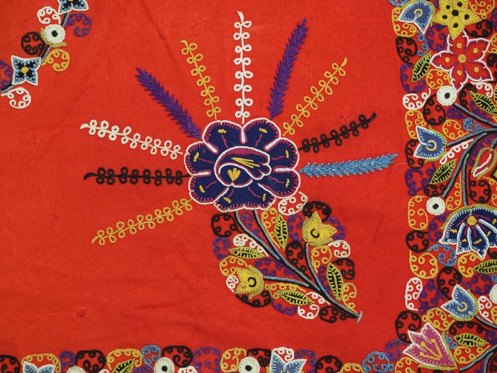 A square red felt textile decorated with polychrome silk chain-stitch embroidery and floral medallion applique motifs. View XI