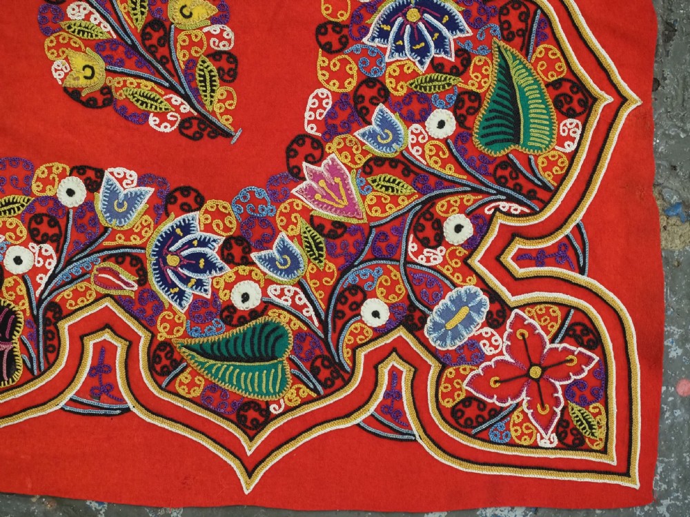 A square red felt textile decorated with polychrome silk chain-stitch embroidery and floral medallion applique motifs. View XII