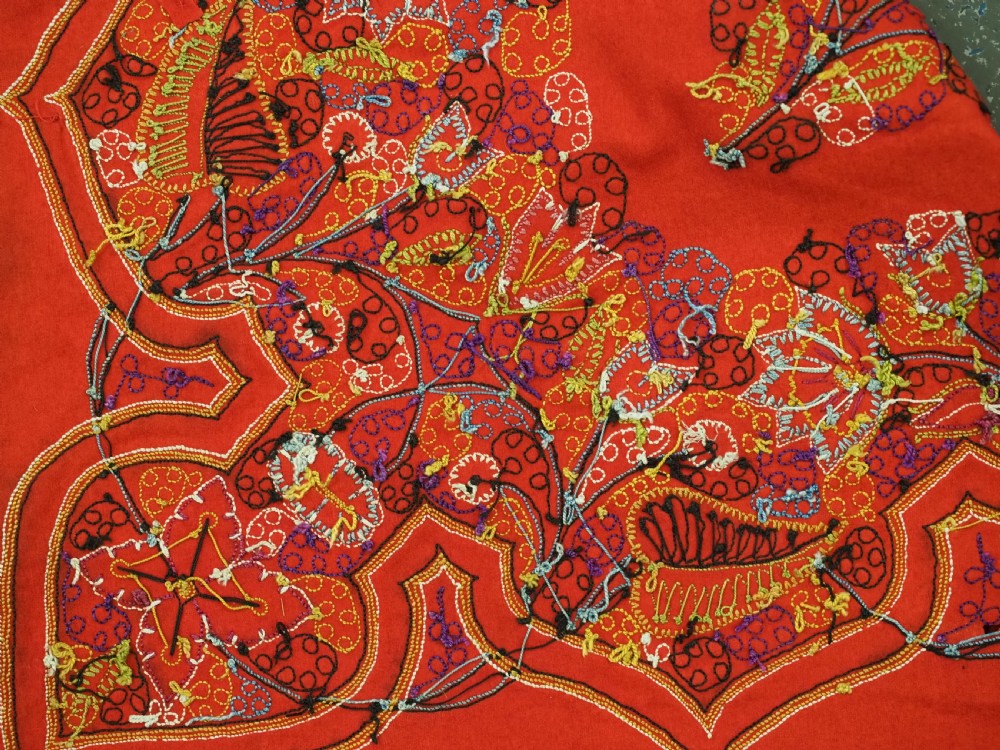 A square red felt textile decorated with polychrome silk chain-stitch embroidery and floral medallion applique motifs. View XIII