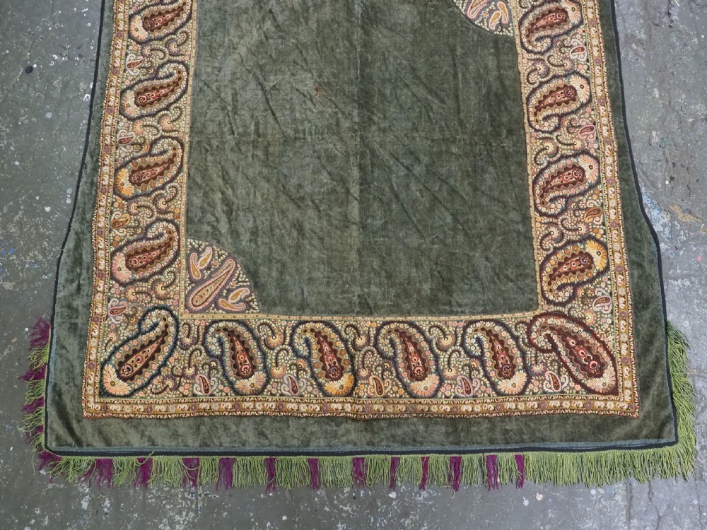 An antique rectangular olive green velvet textile decorated with intricate silk paisley embroidered borders and a fringed edge. View V