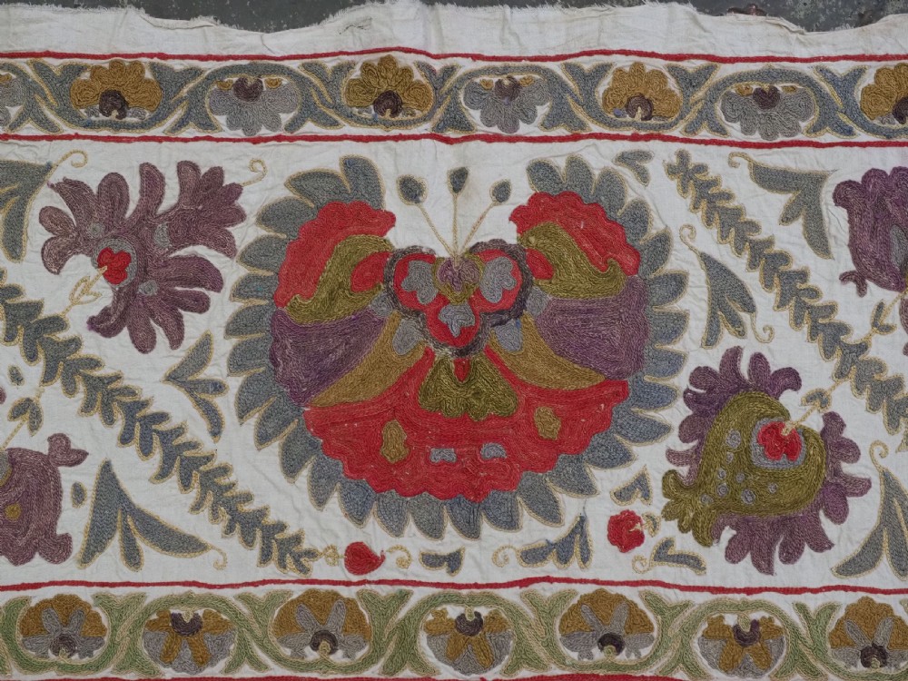 A rectangular embroidered suzani textile featuring a central diamond lattice pattern surrounded by a border of large floral medallions on a cream background. View VIII