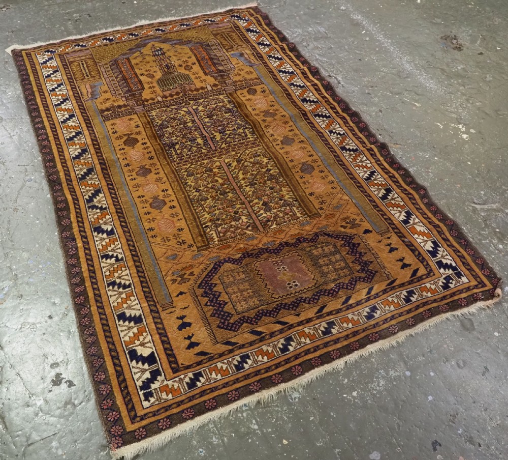 A rectangular handwoven camel wool prayer rug displaying a stylized central mihrab arch motif and geometric decorative borders. View II