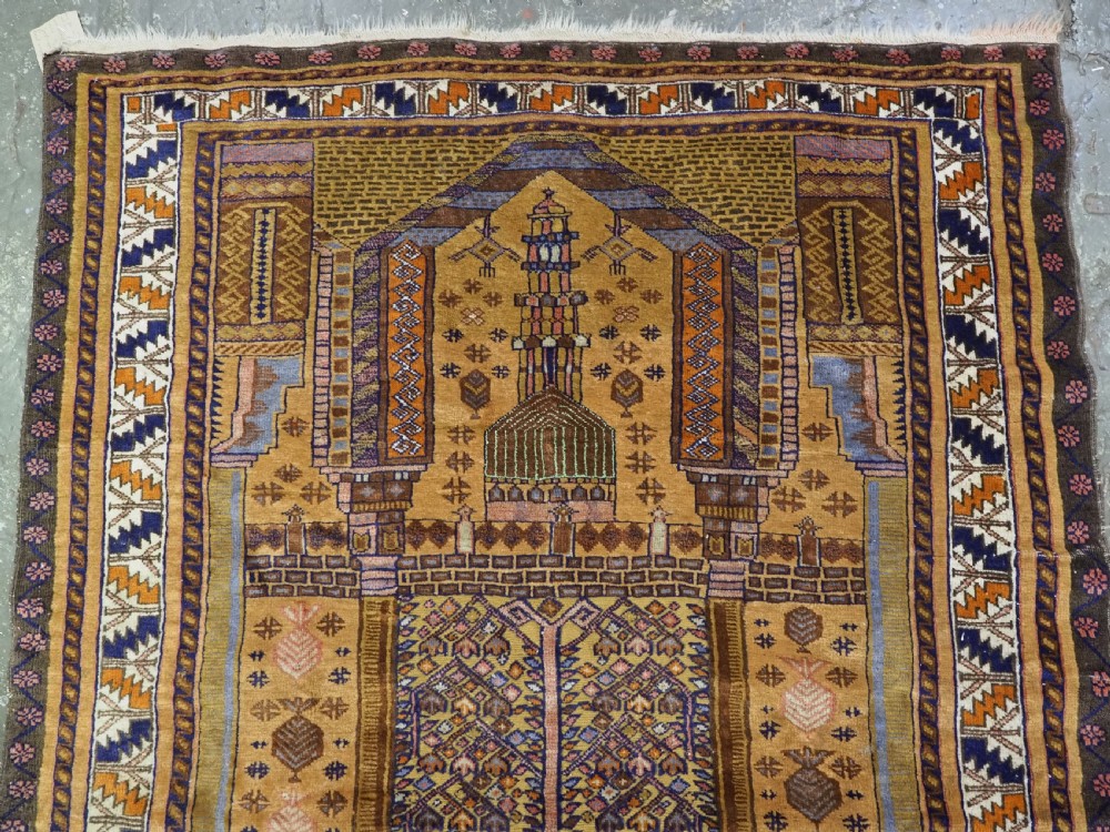A rectangular handwoven camel wool prayer rug displaying a stylized central mihrab arch motif and geometric decorative borders. View III