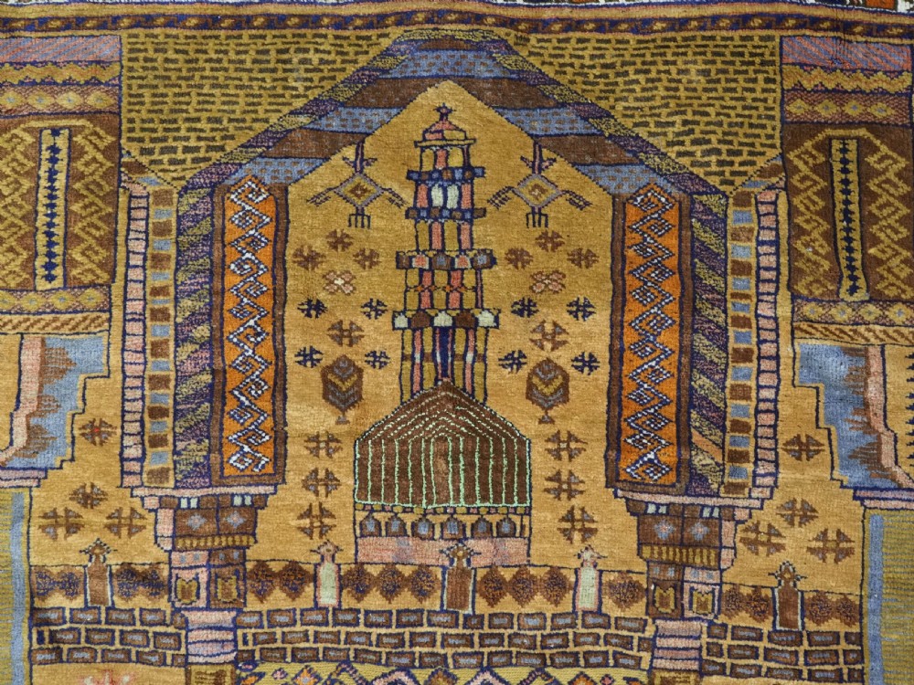 A rectangular handwoven camel wool prayer rug displaying a stylized central mihrab arch motif and geometric decorative borders. View VIII