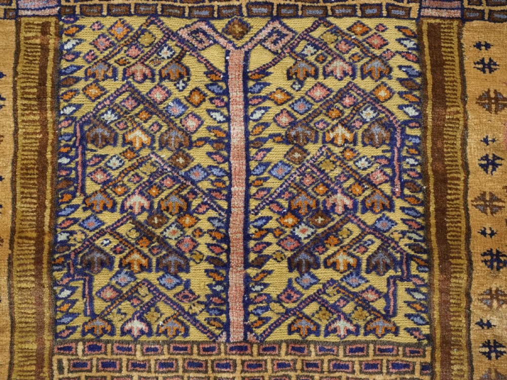 A rectangular handwoven camel wool prayer rug displaying a stylized central mihrab arch motif and geometric decorative borders. View IX