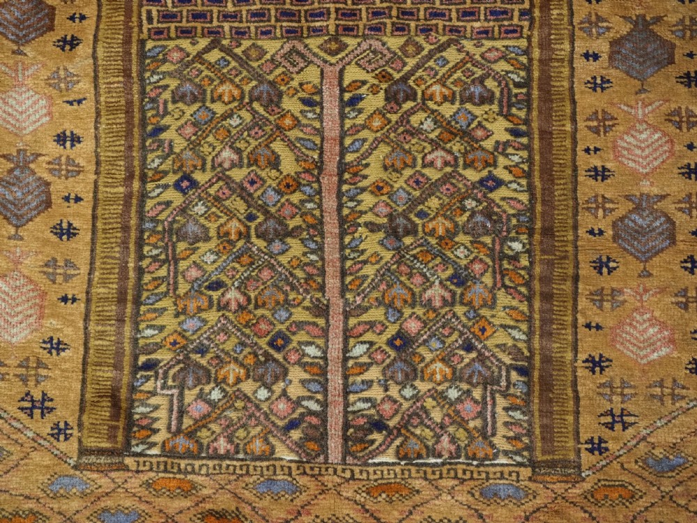 A rectangular handwoven camel wool prayer rug displaying a stylized central mihrab arch motif and geometric decorative borders. View X
