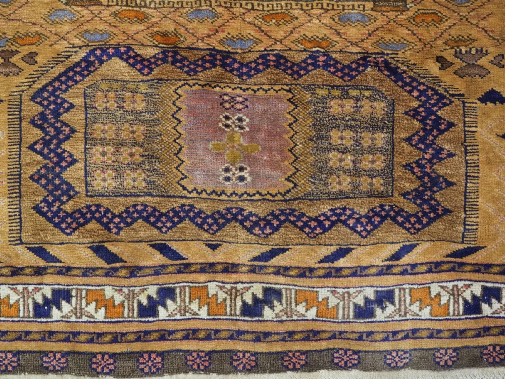 A rectangular handwoven camel wool prayer rug displaying a stylized central mihrab arch motif and geometric decorative borders. View XI