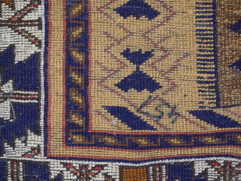 A rectangular handwoven camel wool prayer rug displaying a stylized central mihrab arch motif and geometric decorative borders. View XIII