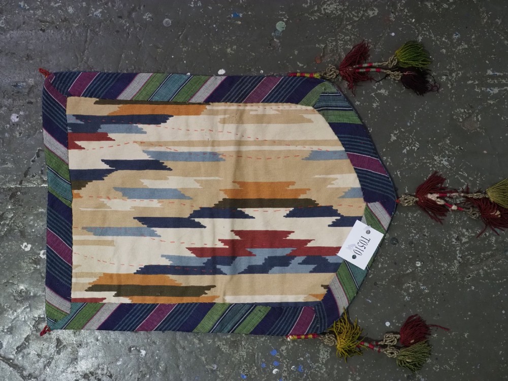 An antique Uzbek shield-shaped red wool textile embroidered with colourful silk teardrop motifs and finished with hanging wool tassels. View VIII