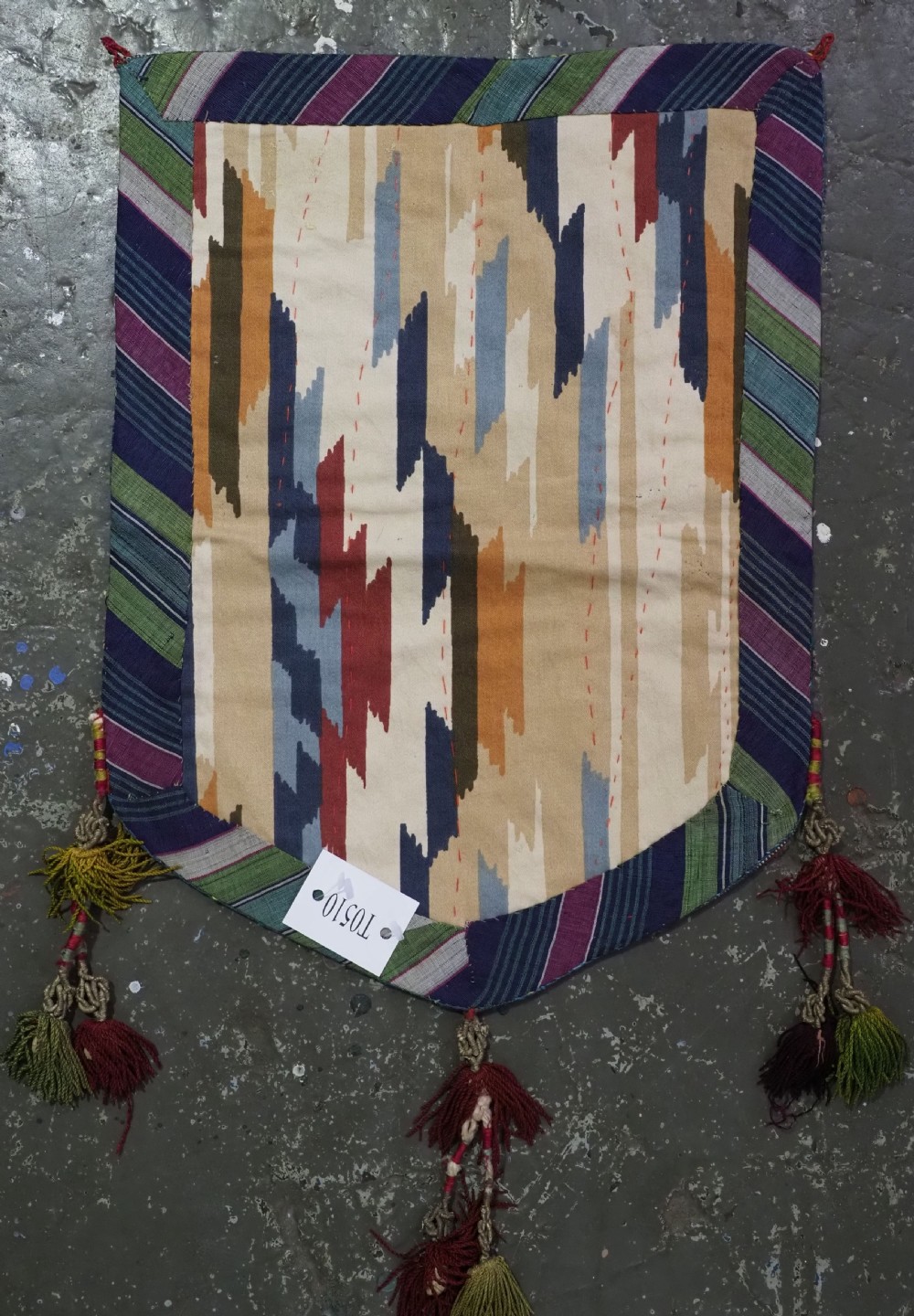 An antique Uzbek shield-shaped red wool textile embroidered with colourful silk teardrop motifs and finished with hanging wool tassels. View XI