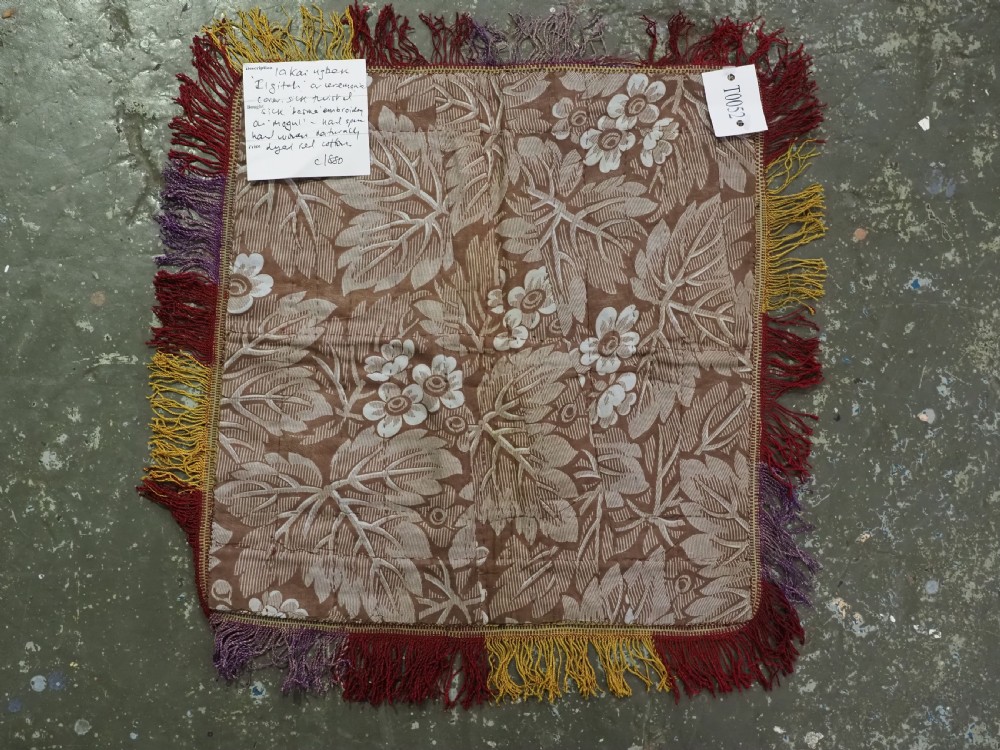 A square red embroidered Uzbek Lakai tribal ilgich wall hanging featuring solar medallions, geometric borders, and coloured fringe. View VII
