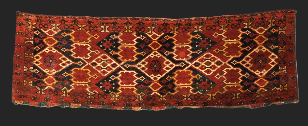 A horizontal rectangular antique Ersari Beshir Turkmen torba textile woven in deep red wool with geometric ikat diamond patterns.