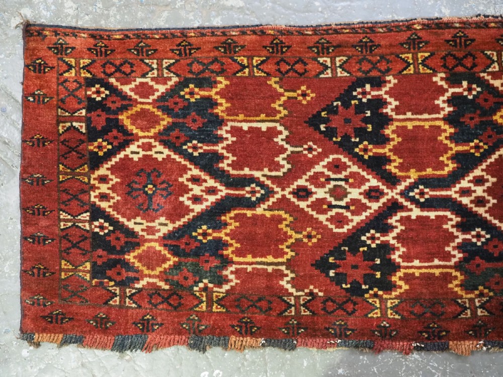 A horizontal rectangular antique Ersari Beshir Turkmen torba textile woven in deep red wool with geometric ikat diamond patterns. View II