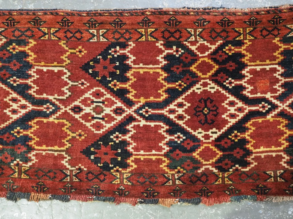 A horizontal rectangular antique Ersari Beshir Turkmen torba textile woven in deep red wool with geometric ikat diamond patterns. View III