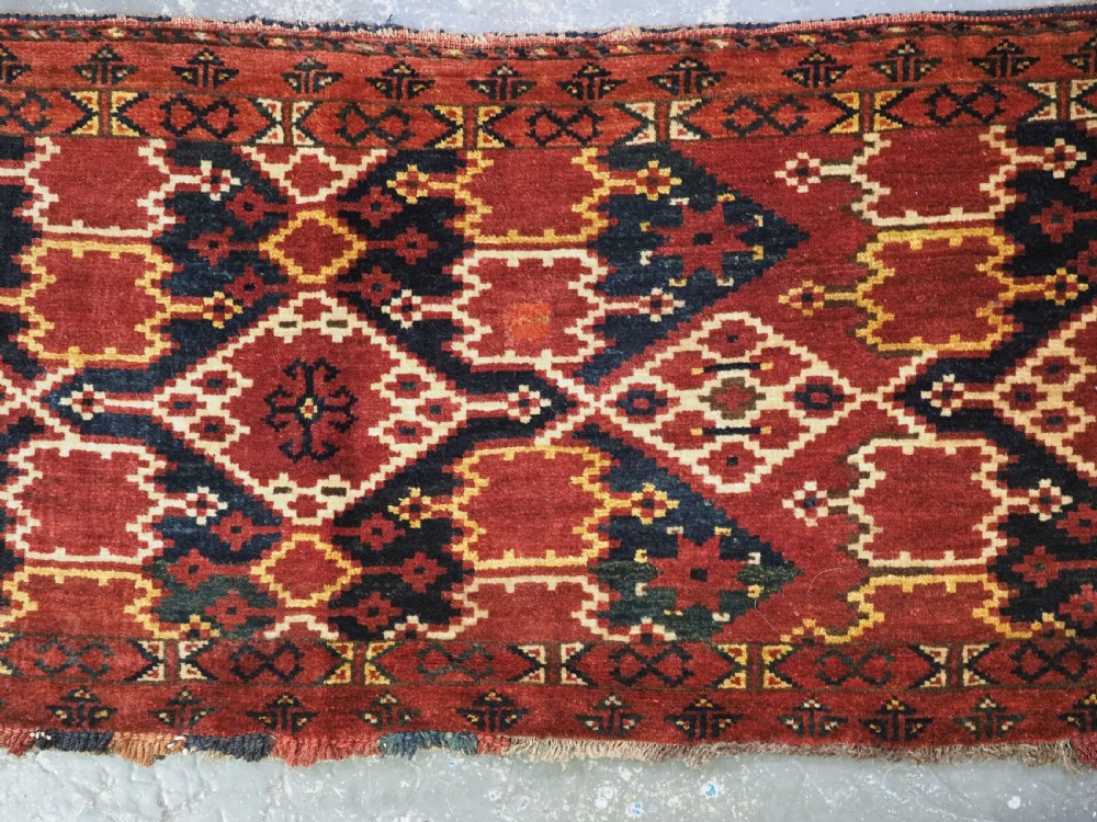 A horizontal rectangular antique Ersari Beshir Turkmen torba textile woven in deep red wool with geometric ikat diamond patterns. View IV
