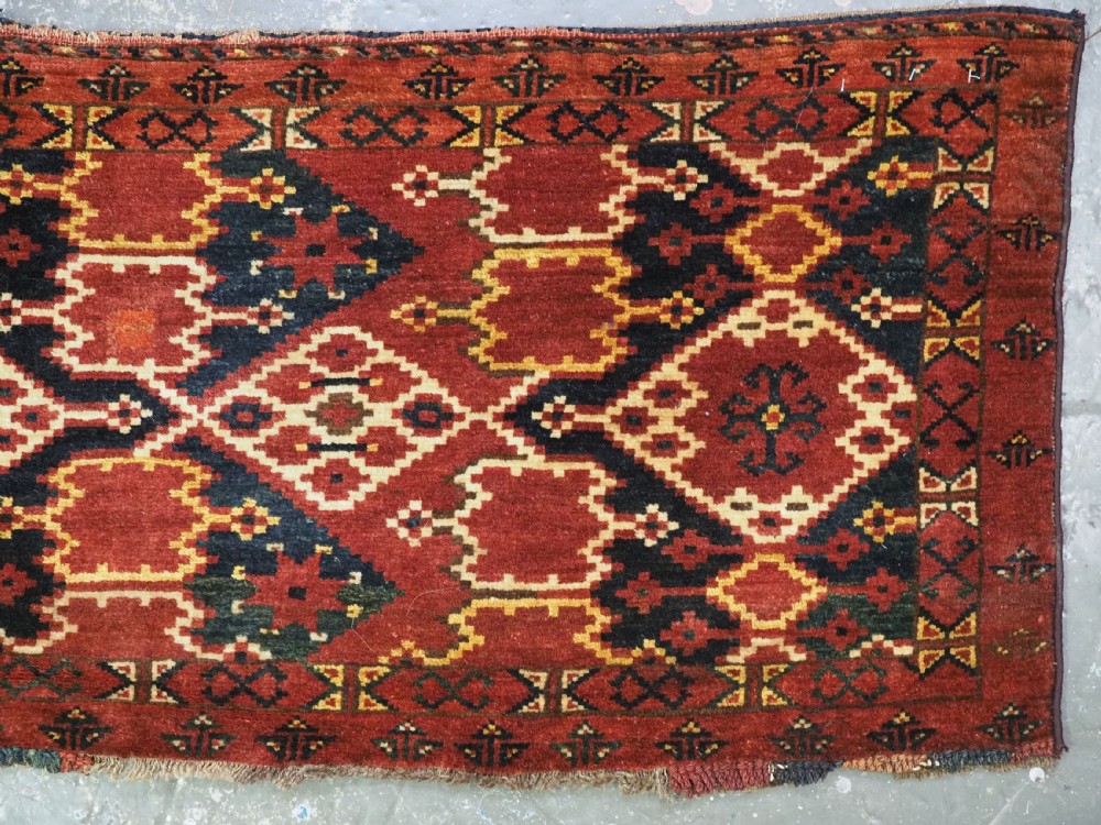 A horizontal rectangular antique Ersari Beshir Turkmen torba textile woven in deep red wool with geometric ikat diamond patterns. View V