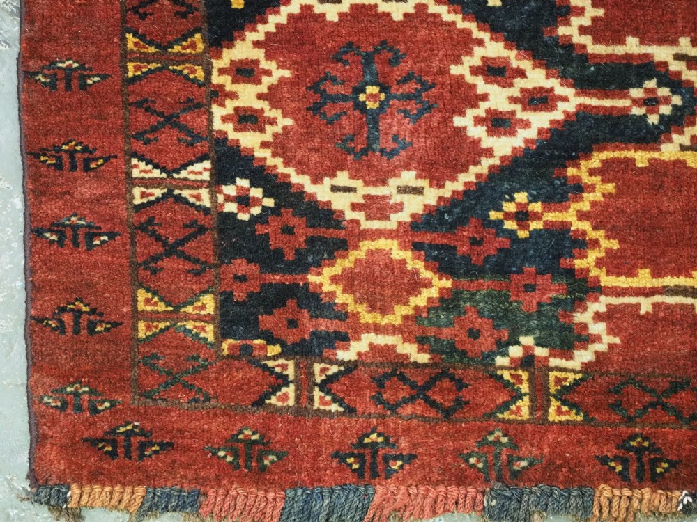 A horizontal rectangular antique Ersari Beshir Turkmen torba textile woven in deep red wool with geometric ikat diamond patterns. View VII