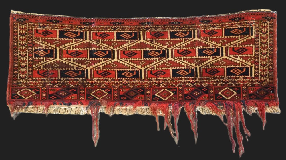 A rectangular hand-woven Tekke Turkmen torba panel featuring deep red, navy blue, and ivory geometric patterns with lower wool fringing.