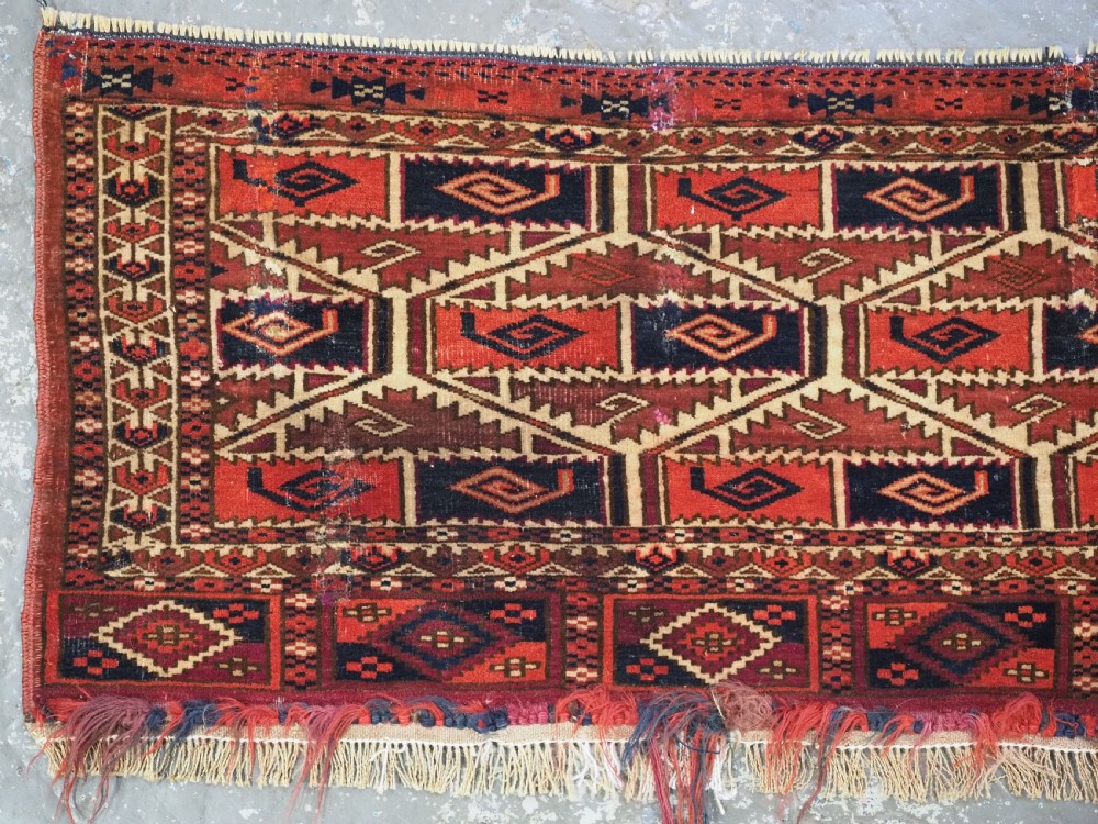 A rectangular hand-woven Tekke Turkmen torba panel featuring deep red, navy blue, and ivory geometric patterns with lower wool fringing. View II