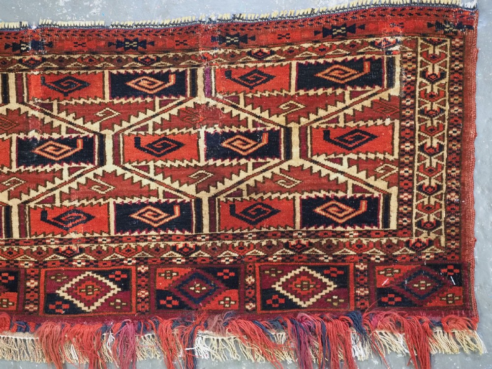 A rectangular hand-woven Tekke Turkmen torba panel featuring deep red, navy blue, and ivory geometric patterns with lower wool fringing. View IV