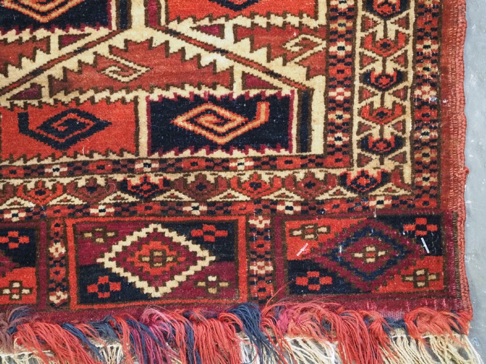 A rectangular hand-woven Tekke Turkmen torba panel featuring deep red, navy blue, and ivory geometric patterns with lower wool fringing. View X