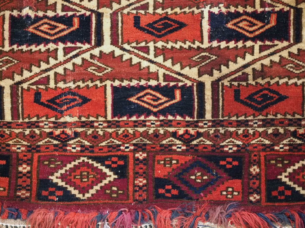 A rectangular hand-woven Tekke Turkmen torba panel featuring deep red, navy blue, and ivory geometric patterns with lower wool fringing. View XI