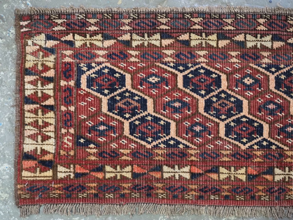 A horizontal woven antique Turkmen torba panel in deep terracotta red, navy blue, and cream, featuring repeating geometric octagonal Schemle gul motifs across the field. View II