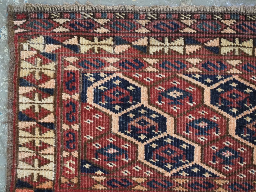 A horizontal woven antique Turkmen torba panel in deep terracotta red, navy blue, and cream, featuring repeating geometric octagonal Schemle gul motifs across the field. View V