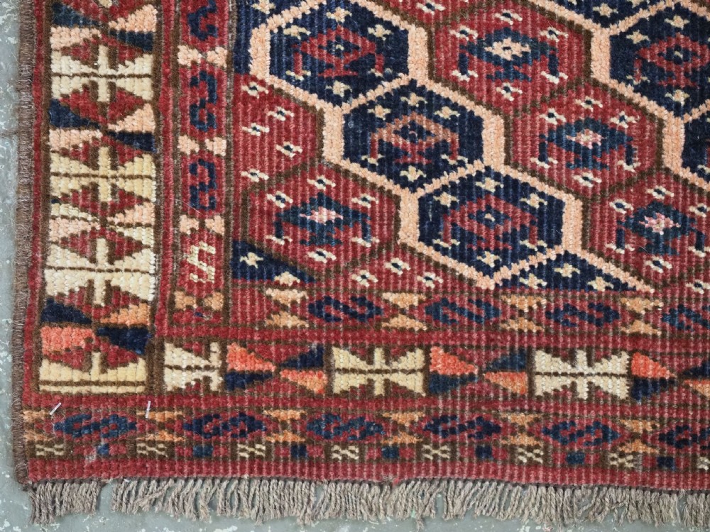 A horizontal woven antique Turkmen torba panel in deep terracotta red, navy blue, and cream, featuring repeating geometric octagonal Schemle gul motifs across the field. View VI