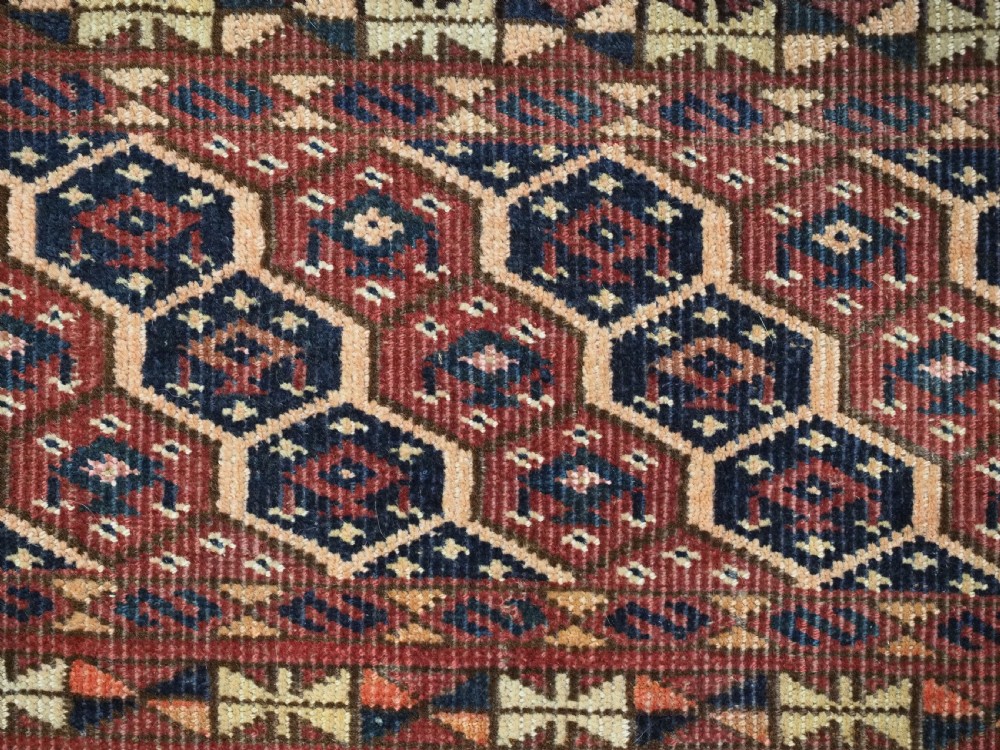 A horizontal woven antique Turkmen torba panel in deep terracotta red, navy blue, and cream, featuring repeating geometric octagonal Schemle gul motifs across the field. View VII