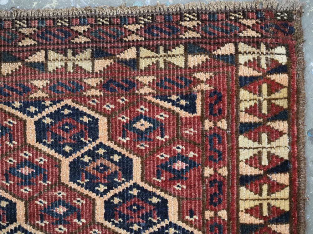 A horizontal woven antique Turkmen torba panel in deep terracotta red, navy blue, and cream, featuring repeating geometric octagonal Schemle gul motifs across the field. View VIII