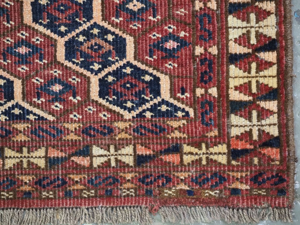 A horizontal woven antique Turkmen torba panel in deep terracotta red, navy blue, and cream, featuring repeating geometric octagonal Schemle gul motifs across the field. View IX