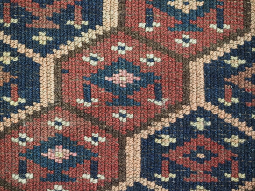 A horizontal woven antique Turkmen torba panel in deep terracotta red, navy blue, and cream, featuring repeating geometric octagonal Schemle gul motifs across the field. View X