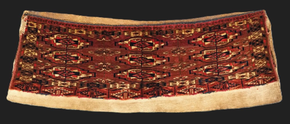 A small rectangular 19th-century Tekke Turkmen wool torba featuring nine geometric guls on a deep red field with an attached cream wool backing.