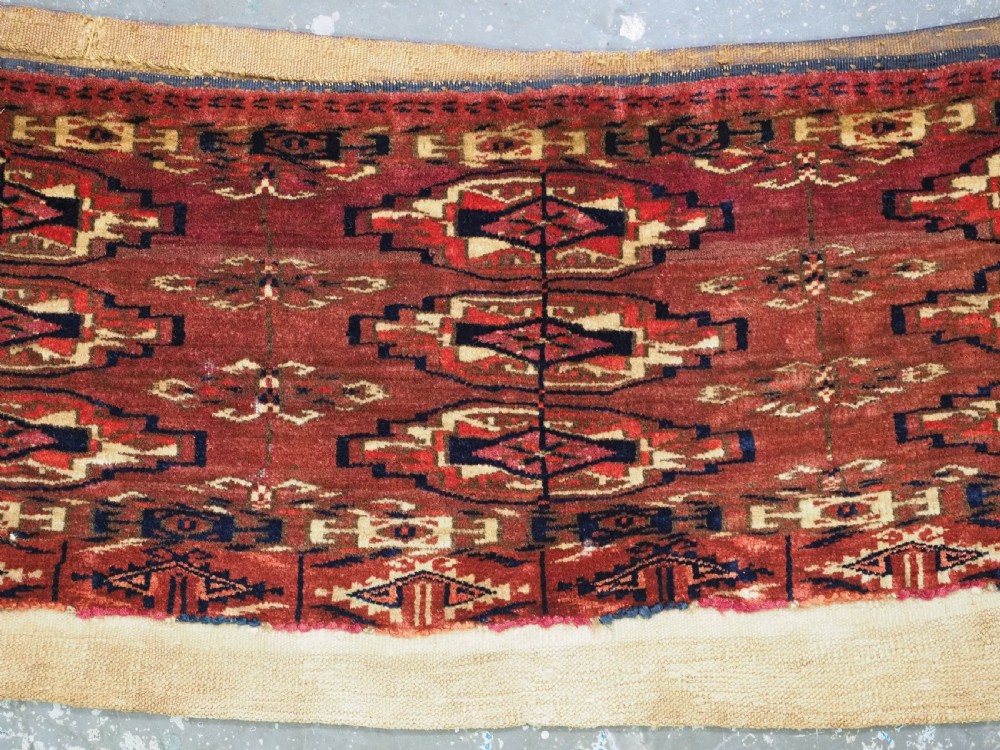 A small rectangular 19th-century Tekke Turkmen wool torba featuring nine geometric guls on a deep red field with an attached cream wool backing. View III